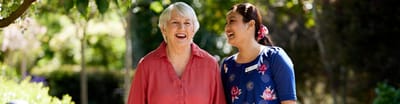 Smiling resident and staff member in a garden
