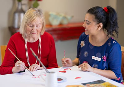 A resident and caregiver painting together