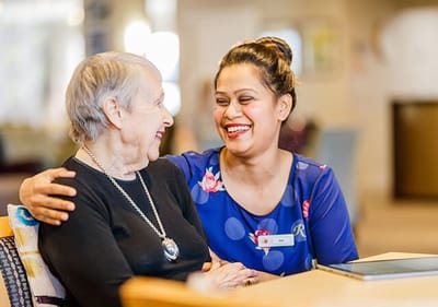 Staff member laughing with a resident in a common area.