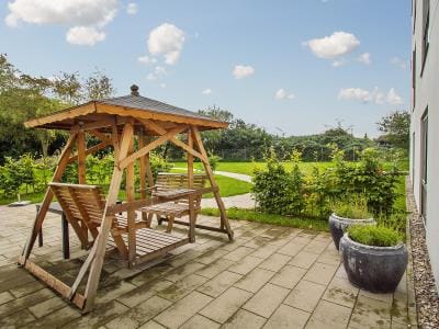 Verdishave, retirement home in Copenhagen, DK — Wooden swing gazebo in a landscaped outdoor area