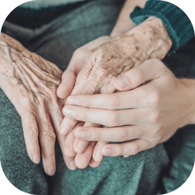 Close-up of elder and caregiver holding hands.