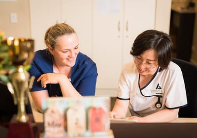 Two caregivers engaging over paperwork