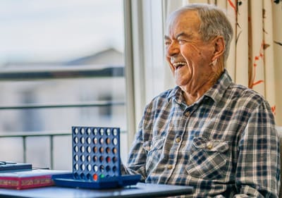 Elderly man laughing while playing a game.