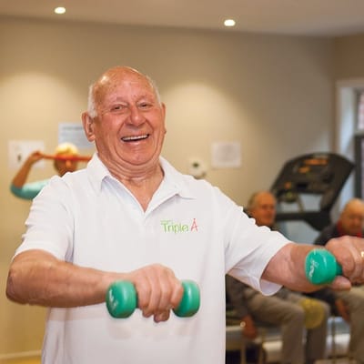 Senior man exercising with weights indoors.
