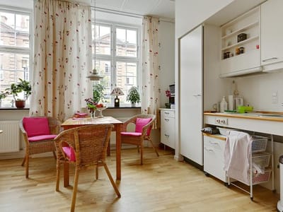 Bright dining area with floral curtains and chairs.