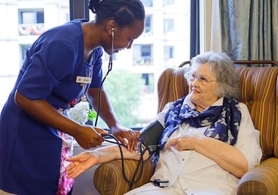 A staff member taking a resident's blood pressure.