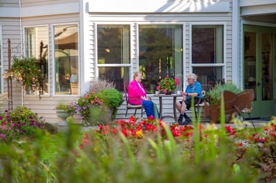 Two seniors enjoying conversation in a garden area.
