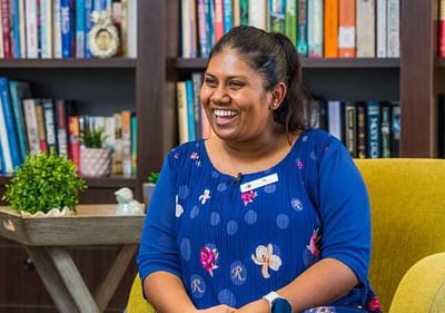 Smiling staff member in a colorful interior setting.