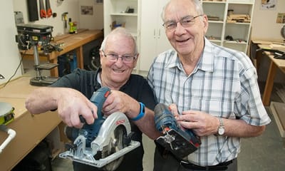 Two residents working on a woodworking project together.