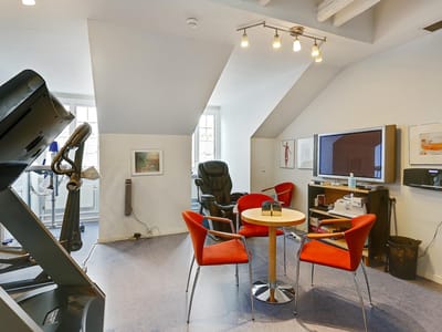 Interior fitness area with exercise equipment and chairs.