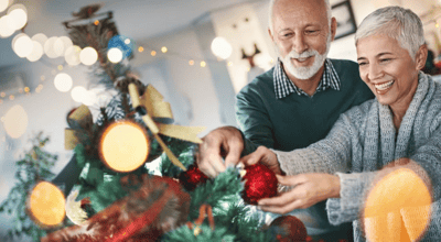 Couple decorating a Christmas tree together.