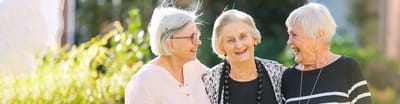 Three elderly women enjoying a moment outdoors.