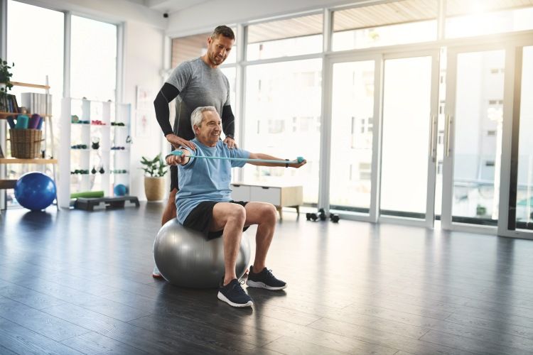 Senior man exercising with trainer indoors