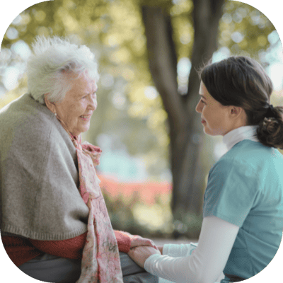Caregiver talking to elderly resident outdoors.