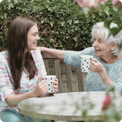 Elderly woman enjoying tea with a young visitor