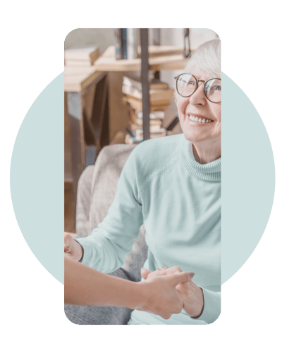 Senior woman smiling while holding hands with staff