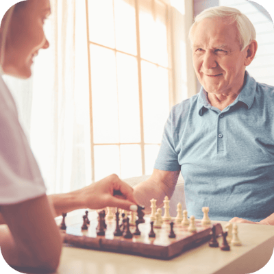Older man playing chess with a caregiver
