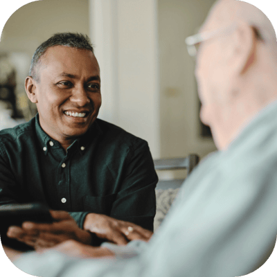 A caregiver and a resident engaged in conversation.