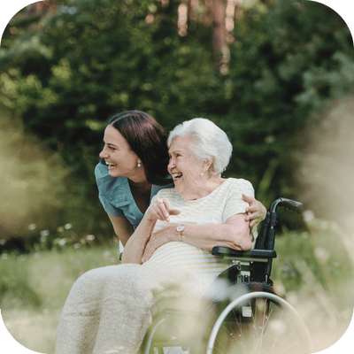 A caregiver and a resident smiling outdoors.
