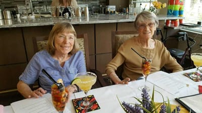 Two residents enjoying drinks at a dining table.