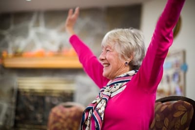 Senior woman smiling with arms raised in celebration