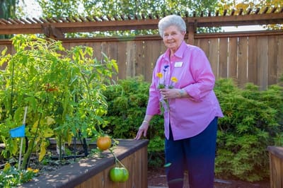 Resident tending to a garden in the facility's outdoor space.