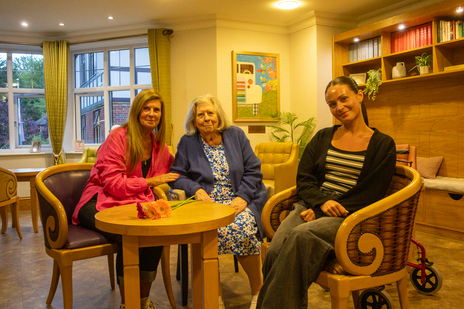 Three women sitting in a cozy facility common area.
