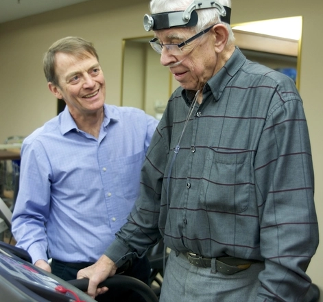 Therapist assisting an elderly man on a treadmill