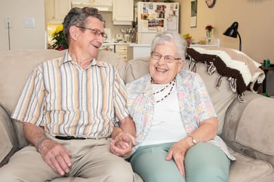 Two seniors enjoying a joyful moment on a couch.