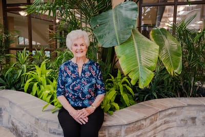 Senior woman smiling in lush indoor greenery