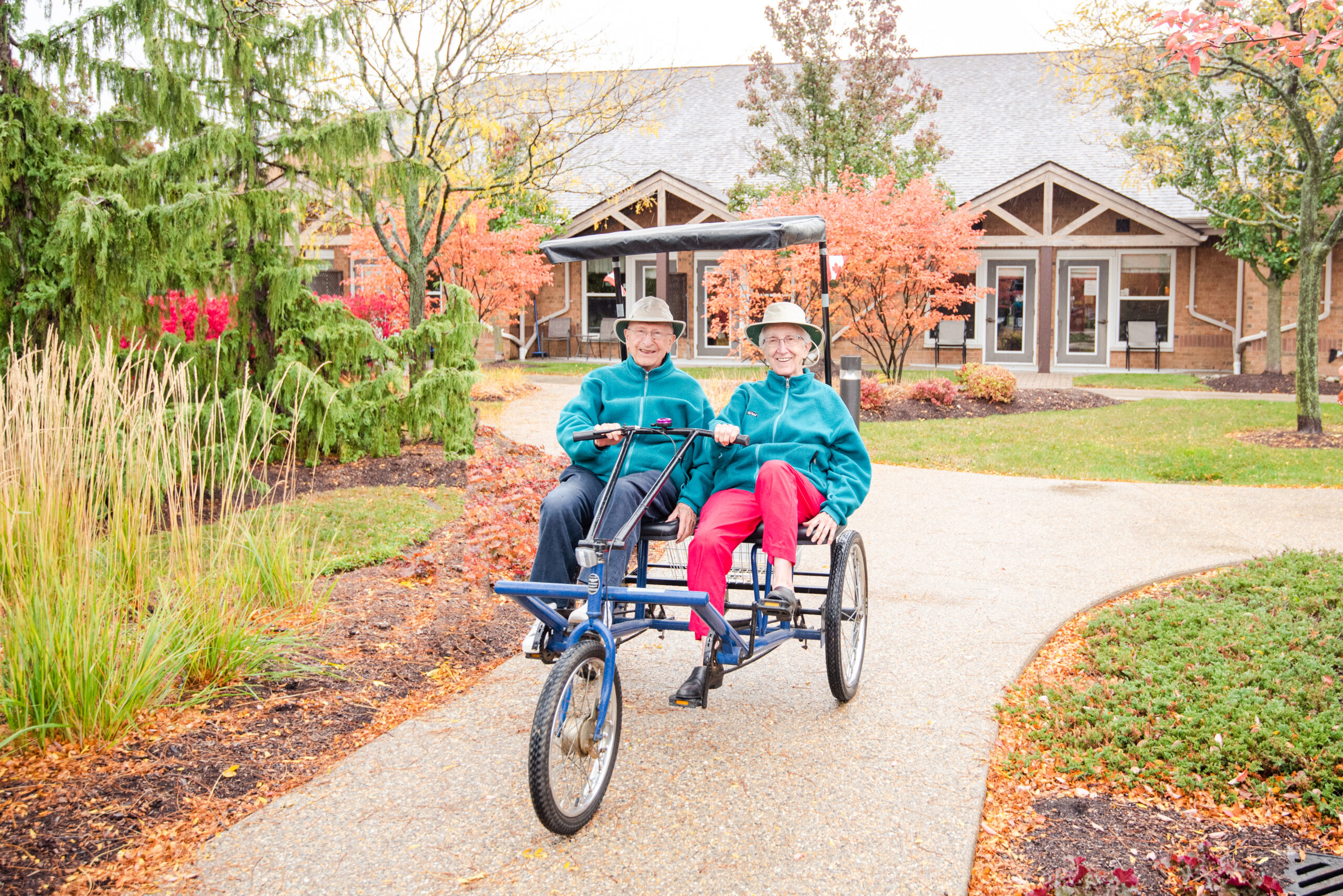 Two residents enjoying a ride on a tricycle outside