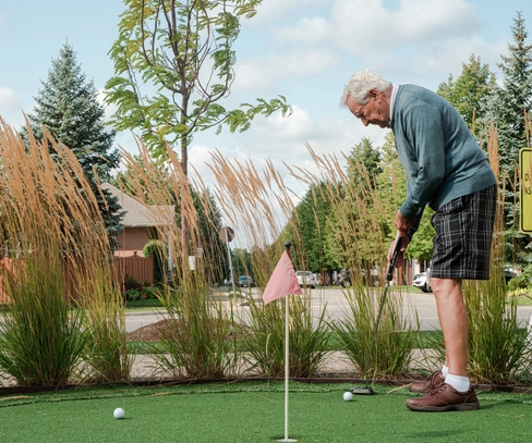 Senior man playing mini-golf outdoors