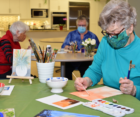 Residents engaged in an art class activity indoors.