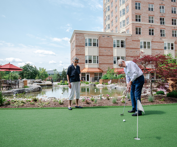 Residents playing mini-golf near a serene pond.