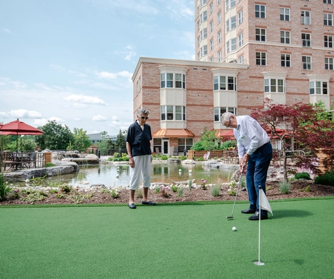 Residents enjoying outdoor putting green activity.