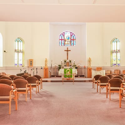 Interior view of a chapel with wooden chairs and stained glass windows