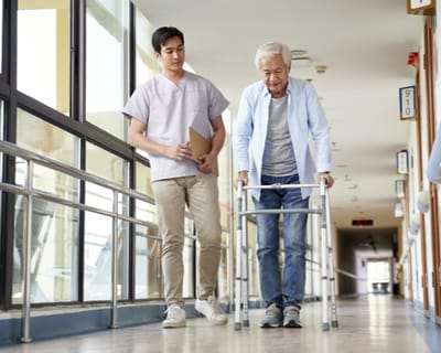 A staff member assists a senior resident in a hallway