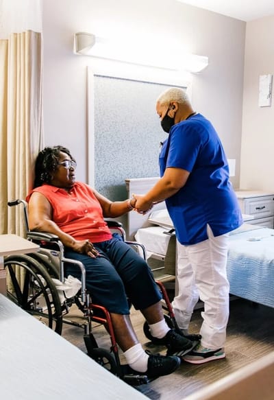 Nurse assisting a resident in a bedroom