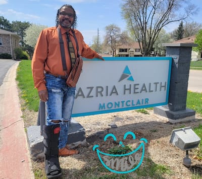 A man standing by the Azria Health Montclair sign