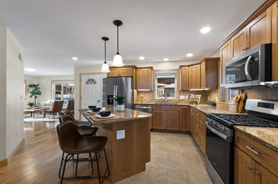 A well-lit kitchen with wooden cabinets and granite countertops