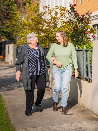 Two residents walking together on a sunny path