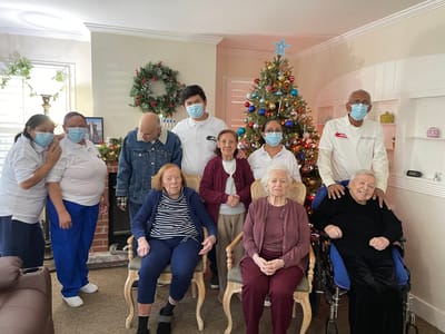 Residents and staff celebrating around a Christmas tree