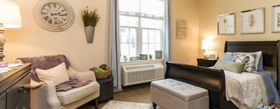 A cozy resident room with a bed and seating area