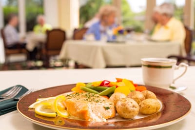 A beautifully plated meal with residents enjoying a dining experience in the background