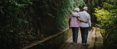 Two seniors walking together on a garden path