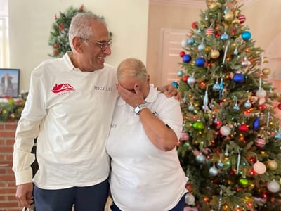 Two staff members celebrating by a Christmas tree