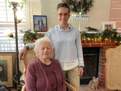 A resident and staff member posing together in a decorated interior