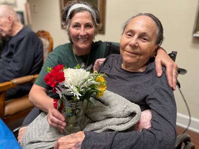 Resident and staff member smiling together with flowers