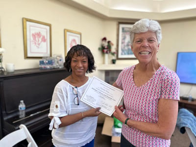 Two staff members presenting an award certificate