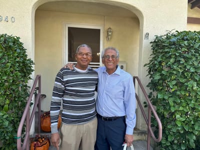 Two residents smiling on the steps of the facility